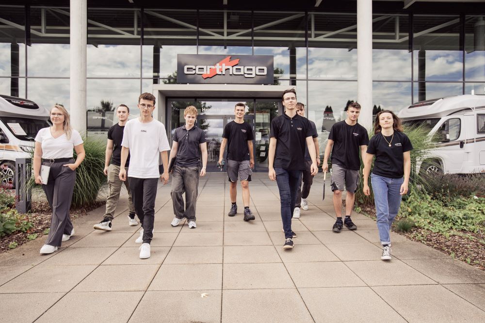 Mehrere Azubis vor dem Eingang der Firma Carthago