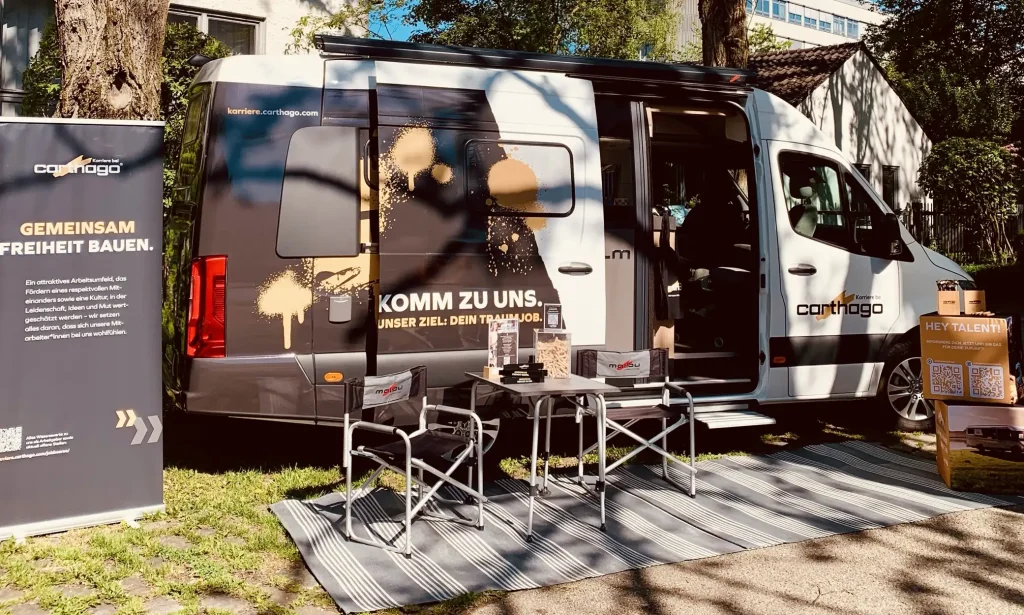 Karriere-Mobil von Carthago mit Infostand, Stühlen und Werbematerialien auf einer Recruiting-Veranstaltung im Freien.