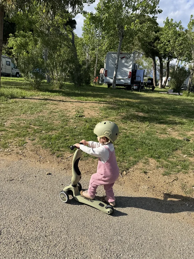 Ein kleiner Moment voller Freiheit: Ein Kind fährt fröhlich mit dem Roller über den Campingplatz – der perfekte Start in einen sonnigen Ferientag.