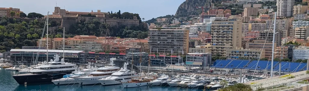 Im Hafen von Monaco reihen sich luxuriöse Yachten vor der imposanten Kulisse aus Palast, Tribünen und Hochhäusern aneinander – ein eindrucksvolles Bild urbaner Eleganz am Mittelmeer.