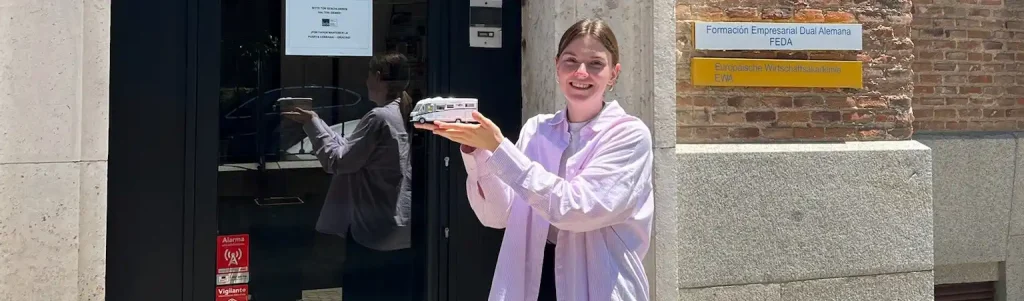 Studentin im Auslandssemester in Spanien, die ein Modell Reisemobil hoch hält