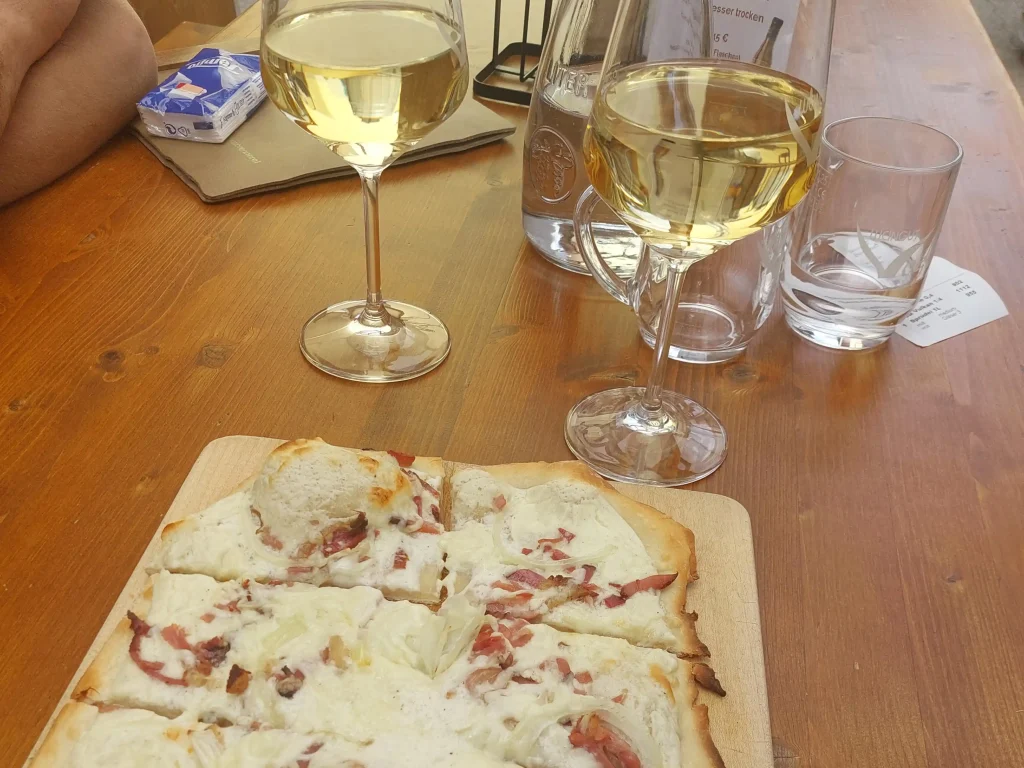 Flammkuchen und zwei Gläser Wein auf einem Tisch