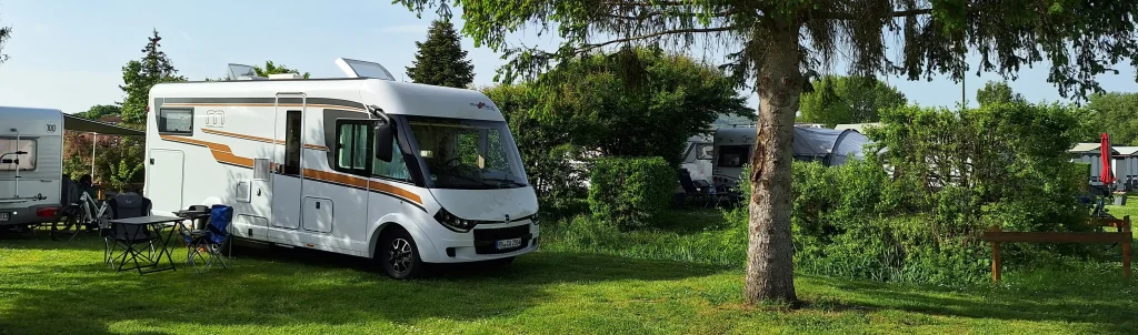 Malibu Reisemobil steht auf einem grünen Stellplatz und wird von der Sonne angestrahlt