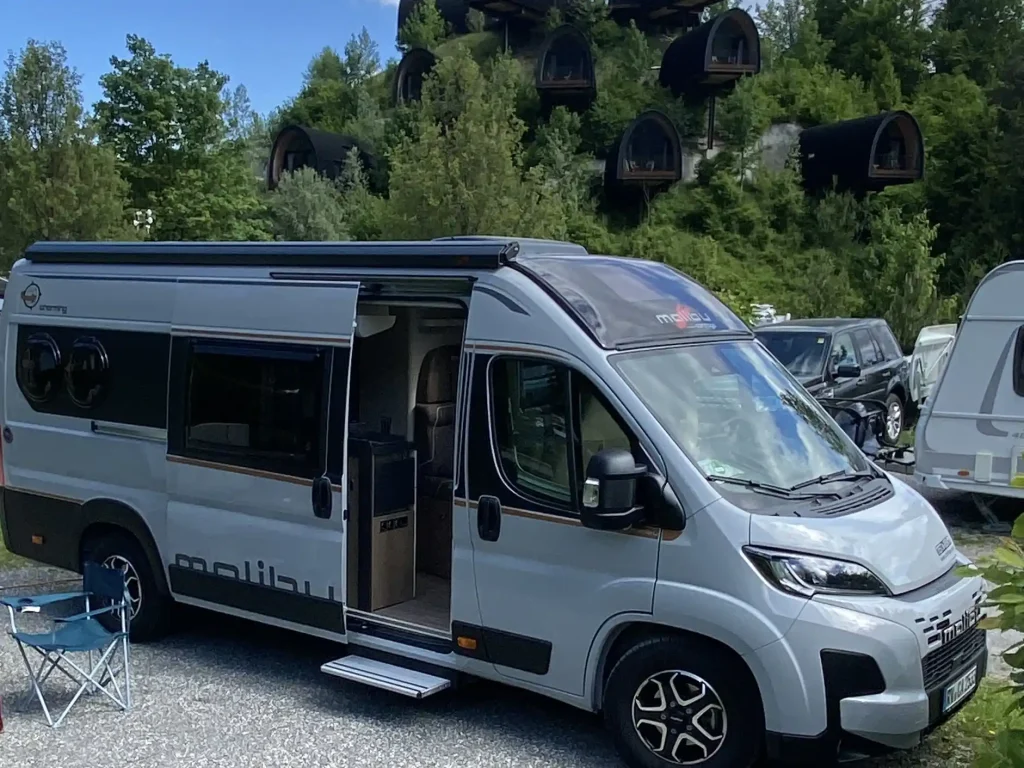 Malibu Van auf Stellplatz in Nenzing mit Bäumen im Hintergrund