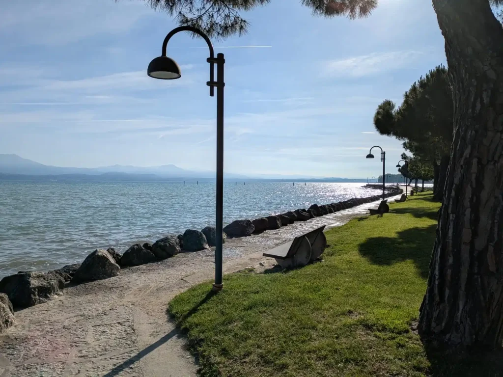 Blick auf eine Fußgängerzone und den Gardasee bei Sonnenschein