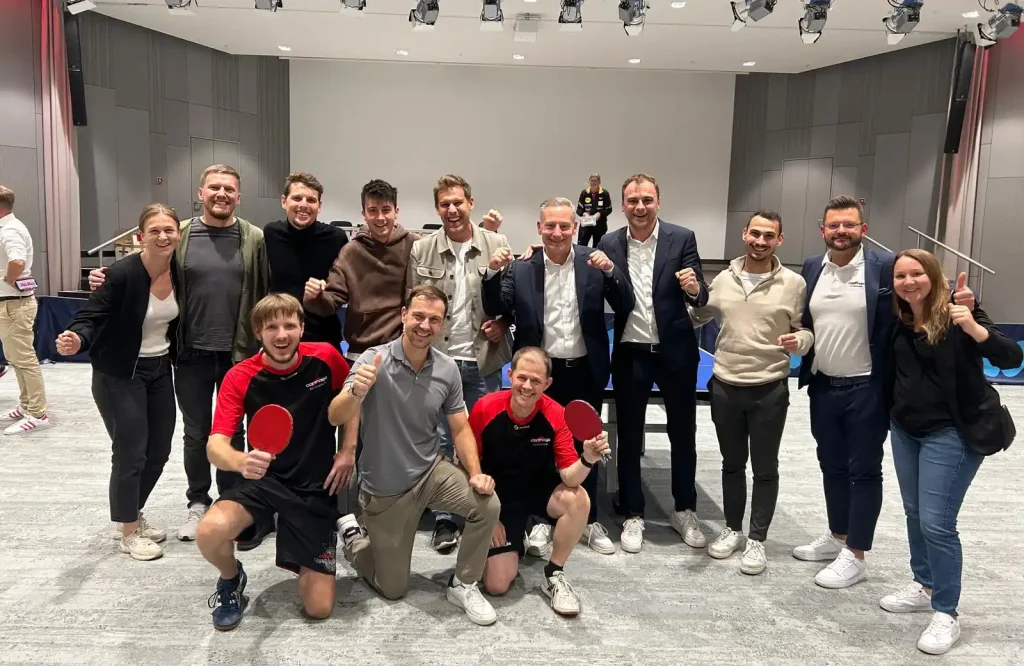Gruppenbild unserer Mitarbeitenden mit einem Tischtennis Team und Timo Boll