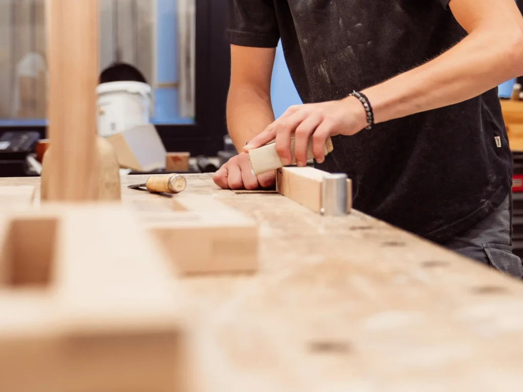 Hände die ein Holz schleifen