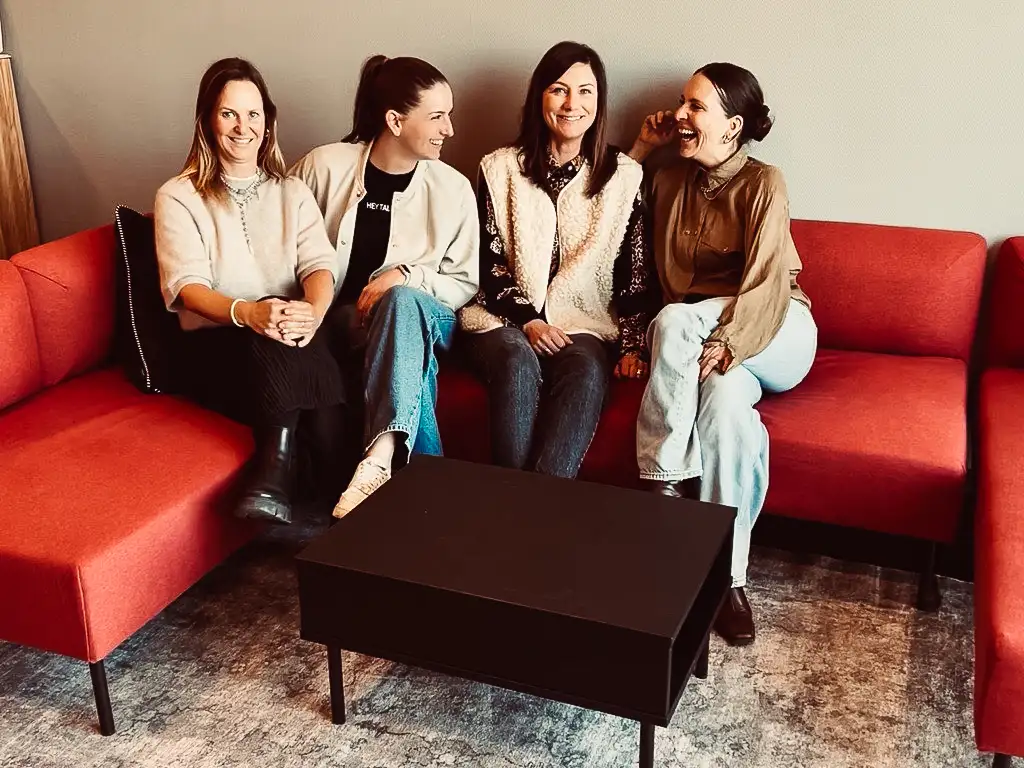 Vier Frauen sitzend auf einem roten Sofa